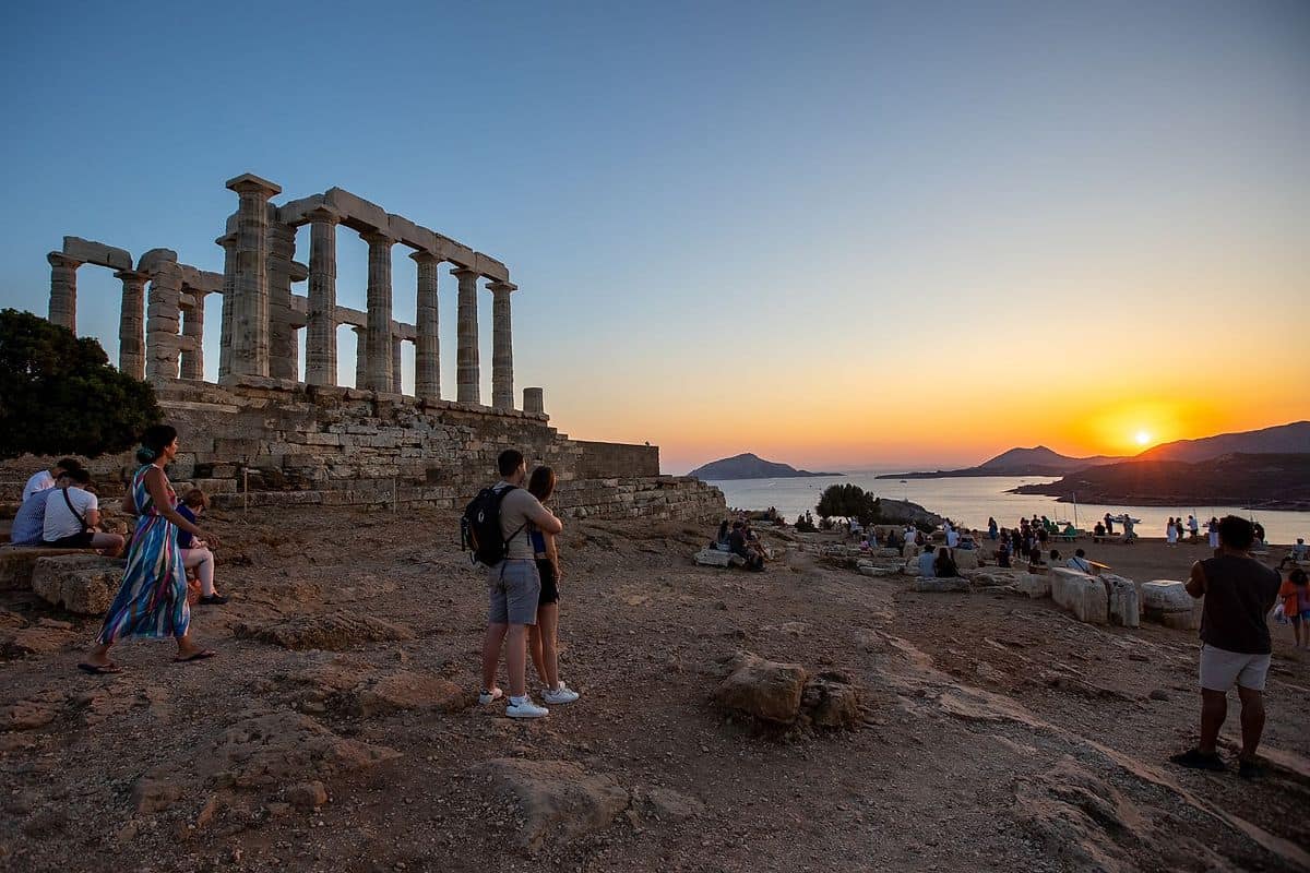 Cape Sounion tour visitors at the Temple of Poseidon at sunset with the Aegean Sea behind