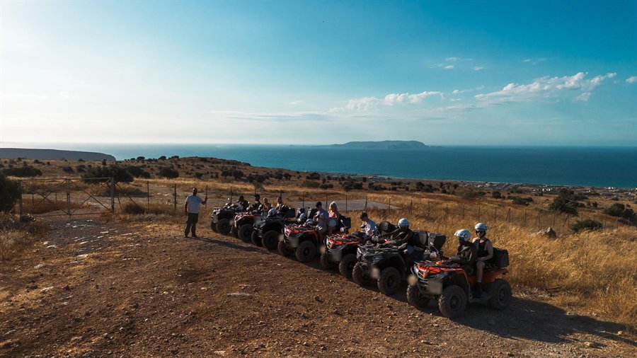 Crete quad tour group lined up on ATVs on a dirt track high above the sea