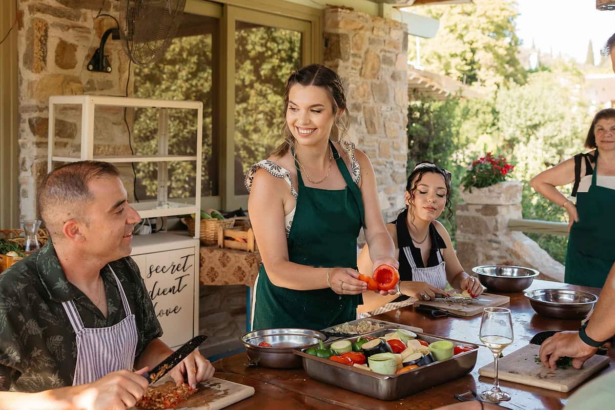 Naxos cooking class with guests in aprons chopping fresh vegetables together at a sunny outdoor table