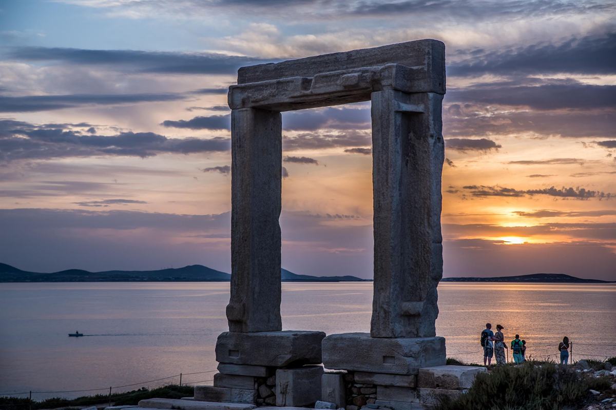 Naxos tour visitors watching the sunset behind the Portara marble gate of the Temple of Apollo