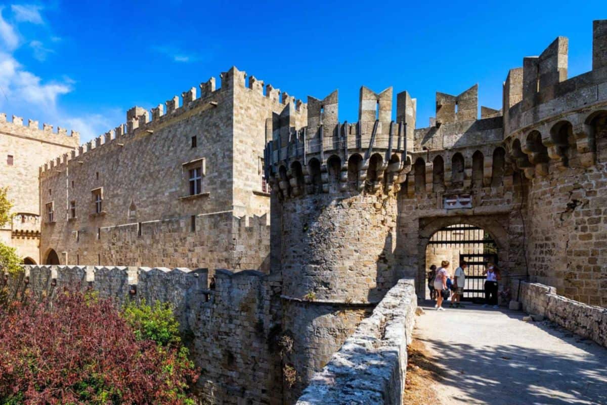Rhodes old town tour visitors at a medieval gate beside the Palace of the Grand Master